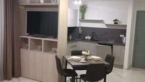 Een moderne keuken met een eethoek, een televisie en een kleine plant.