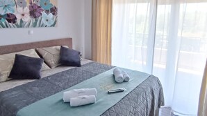 Habitación de hotel con cama, almohadas, manta, toallas, control remoto y un cuadro en la pared.