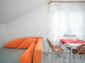 Ein Zimmer mit einem Bett, einem Tisch mit Stühlen und einem Fenster mit Vorhängen.