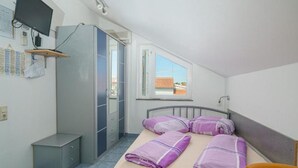 A small, tidy room with a bed, a desk, a chair, a wardrobe, and a window. - Apartments Milka Vodice - Studio Apartment with Terrace (Vodice)