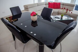 A dining area with a black table, four chairs, and a vase with flowers. - Baru Nativa Beach Apartments (Cartagena)