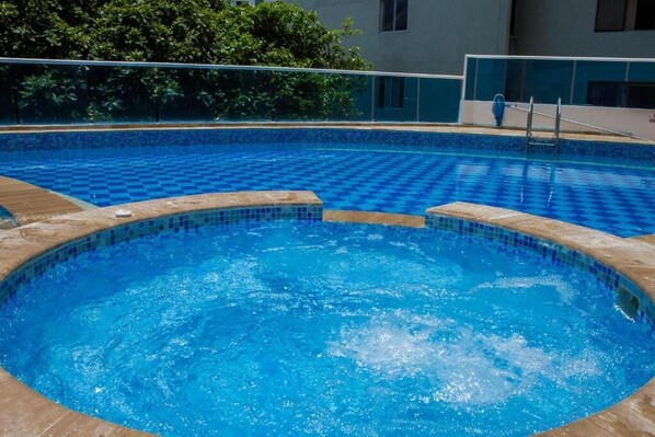 A swimming pool with a checkered pattern, a hot tub, and a poolside area with a railing. - Baru Nativa Beach Apartments (Cartagena)