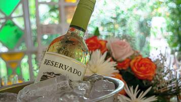 Una botella de vino en un recipiente de vidrio con hielo, rodeado de flores.