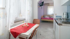 Una habitación con una mesa de comedor, una cama y un pequeño espacio de cocina.