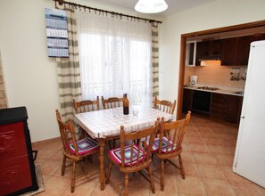 Un comedor con una mesa, sillas y una cocina al fondo.