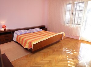 Un dormitorio con una cama de madera, una mesita de noche, una lámpara y una ventana con cortinas.