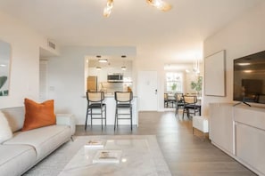 Ein modernes Wohnzimmer mit Sofa, Couchtisch und Essbereich mit Stühlen.