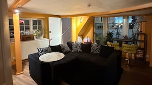 A living room with a black sofa, a round coffee table, and a staircase leading to an upper floor. - Cozy flat in the heart of the Lanes, with a game room and space up to 4 people (Brighton and Hove)