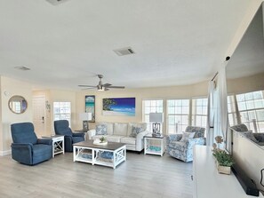 Un salon avec un ventilateur de plafond, un canapé, une table basse et un téléviseur.