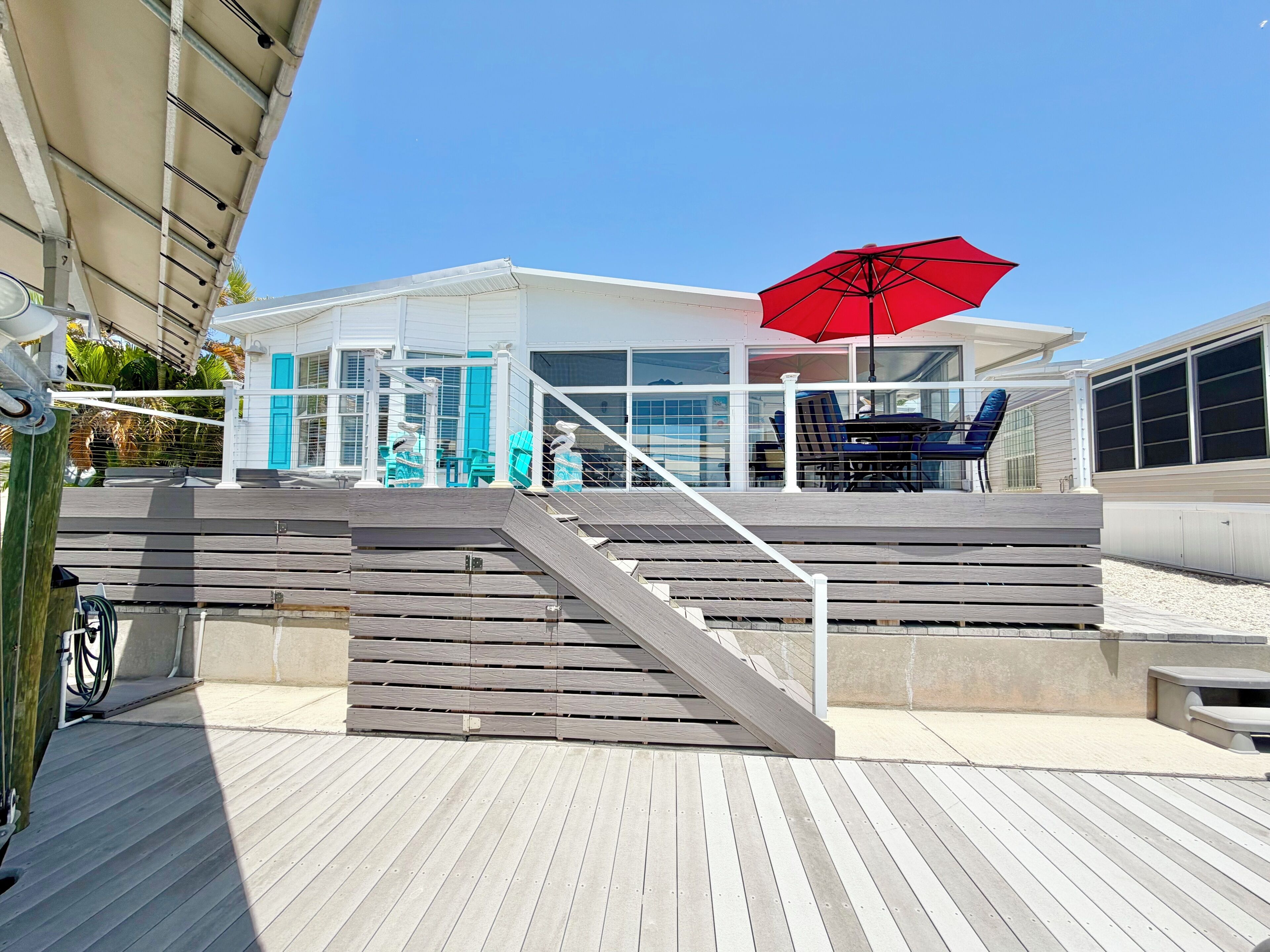 A wooden deck with a staircase leading to a covered area with outdoor furniture.