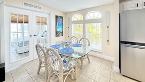 A kitchen with a dining area, white cabinetry, and a refrigerator. - Waterfront Gulf Access Home - Dock, Hot Tub, Sunset Views (Saint James City)