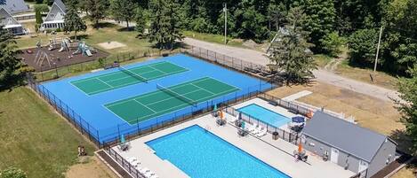 Un court de tennis et une piscine, avec un bâtiment en arrière-plan.