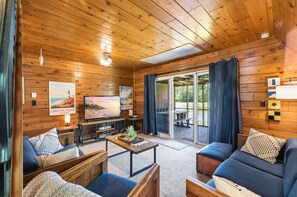 Ein gemütliches Blockhaus mit Holzwänden, einer Sofagarnitur, einem Couchtisch und einem Fernseher.