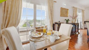 En matplats med ett bord dukat för frukost, en utsikt genom fönstret och en tavla på väggen.