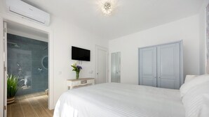 Une chambre avec un grand lit, un téléviseur fixé au mur, une armoire et un espace douche.