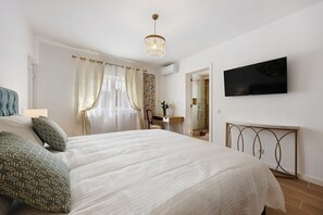 A bedroom with a bed, a desk, a TV, and a shower area. - 'Encanto - Premium' Room with Shared Pool, Wi-Fi, and Air Conditioning (Alvor)