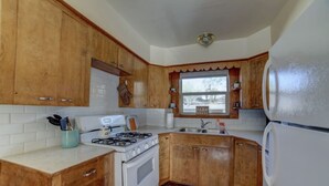 Eine Küche mit Holzausstattung, einem Herd, einem Kühlschrank und einem Fenster mit Blick auf Bäume.