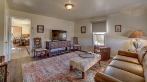 Ein Wohnzimmer mit Fernseher, einer Couch und einem Essbereich mit Stühlen und einem Tisch.