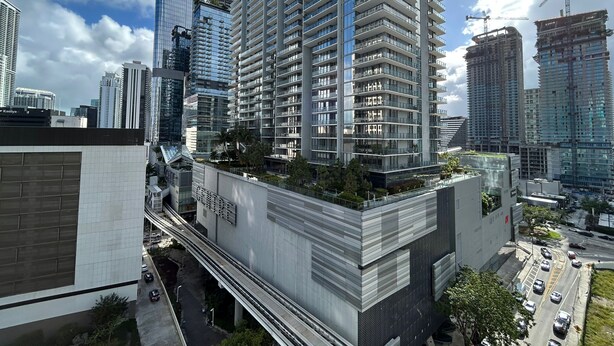 Un edificio de gran altura con diseño moderno, que destaca por su fachada de vidrio y un jardín en la azotea.