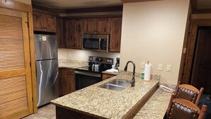Una cocina con armarios de madera, electrodomésticos de acero inoxidable, encimeras de granito y un lavamanos empotrado.