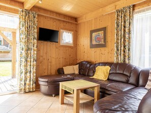 A cozy living room with a brown leather sofa, a small wooden table, a flat-screen TV, and a framed artwork on the wall. - # 32 mit 2 Schlafzimmern für 8 Personen by Interhome (Sankt Georgen am Kreischberg)