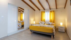 A bedroom with a bed, bedside tables, a wardrobe, and a mirror. - Villa Ti'Twoine - Sea view - Sunsets - (Pointe-Noire)