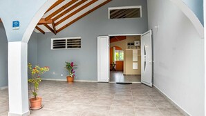 An interior corridor with tiled flooring, a wooden ceiling, and potted plants. - Villa Ti'Twoine - Sea view - Sunsets - (Pointe-Noire)