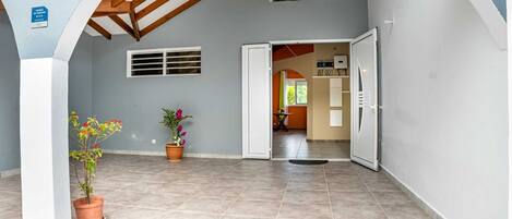 An interior corridor with tiled flooring, a wooden ceiling, and potted plants.