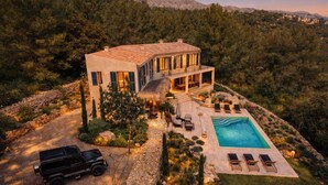 A two-story house with a pool, surrounded by a stone wall and trees. - An oasis in the middle of nature (Pollença)