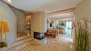 A modern interior with a fireplace, staircase, dining area, and a large plant. - An oasis in the middle of nature (Pollença)