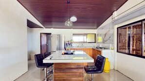 A modern kitchen with a central island, stainless steel appliances, and a wooden ceiling. - Paulos View Lodge (Venecia)