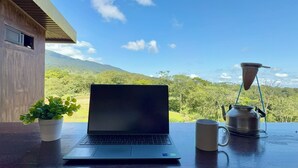 A laptop on a table with a view of a mountain and greenery. - Paulos View Lodge (Venecia)