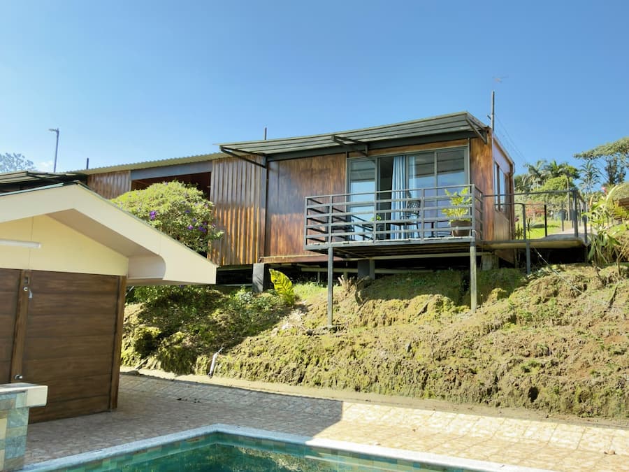 A modern house with a pool, wooden deck, and a view of the surrounding landscape.