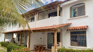 A two-story house with a patio, a wooden table, and a covered seating area. - Casa Coral (Manzanillo)
