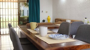 A dining area with a wooden table, chairs, a yellow vase, and a blue and white plate. - Casa Coral (Manzanillo)
