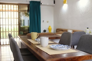 A dining area with a wooden table, chairs, a yellow vase, and a blue and white plate.
