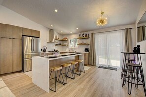 Eine moderne Küche mit Kochinsel, Holzstühlen und einem Essbereich mit Tisch und Sesseln.