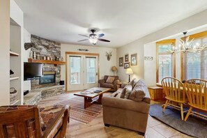 A living room with a fireplace, sofa, coffee table, and wooden chairs.