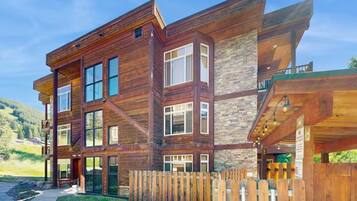 A multi-story wooden house with large windows and a stone facade.