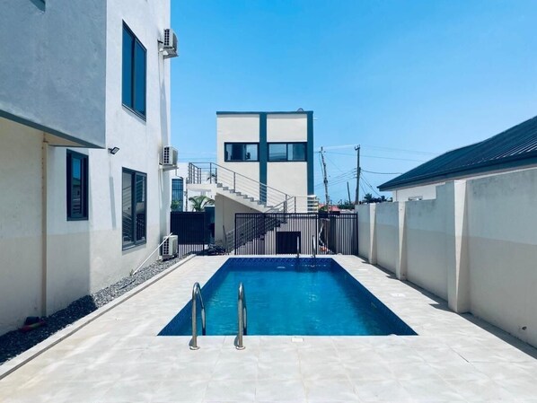 Ein Swimmingpool mit Metallleiter, eine Treppe zu einem Gebäude und ein verschlossener Eingang.