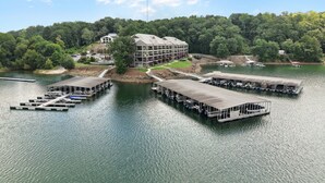 Un hotel junto al lago con barcos amarrados, un edificio con techo inclinado y una ladera boscosa.