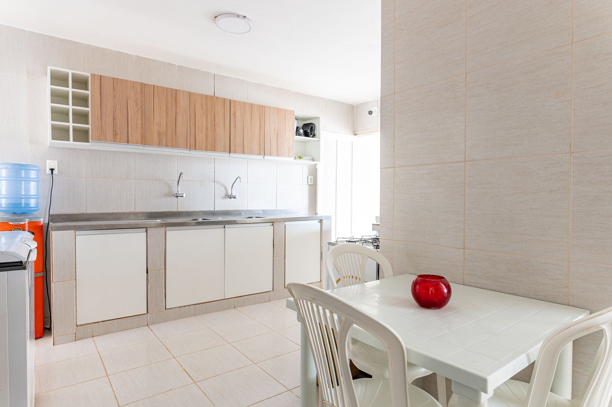 A kitchen with white cabinets, a sink, and a dining area with a table and chairs.