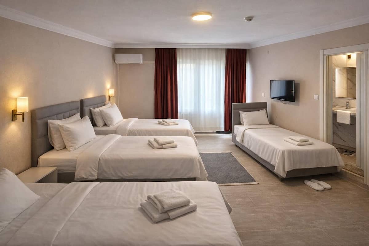 A hotel room with three beds, a TV, a bathroom with a marble sink, and a window with curtains.