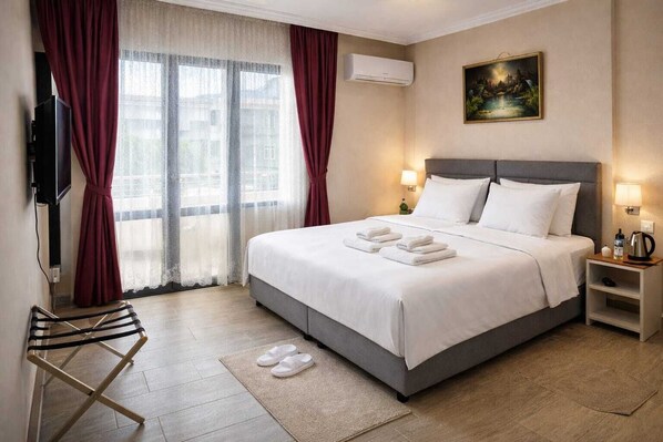 Habitación de hotel con cama, televisión, un cuadro y vistas a edificios a través de la ventana.