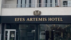 Un hotel de varios pisos con balcones, unidades de aire acondicionado y un letrero que dice 'EFES ARTEMIS HOTEL'.