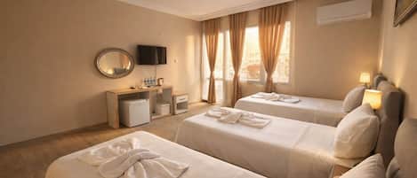 A hotel room with two beds, a desk with a TV, and a window with curtains.