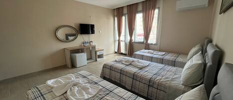 Habitación de hotel con dos camas, un escritorio, un televisor y una ventana con cortinas.