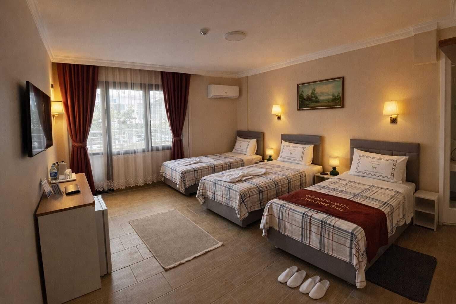 Habitación de hotel con dos camas, un escritorio, un televisor y una ventana con cortinas.