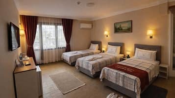 Habitación de hotel con dos camas, un escritorio, un televisor y una ventana con cortinas.