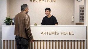 Un mostrador de recepción en el Hotel Artemis con un reloj y un cartel que indica la zona de recepción.